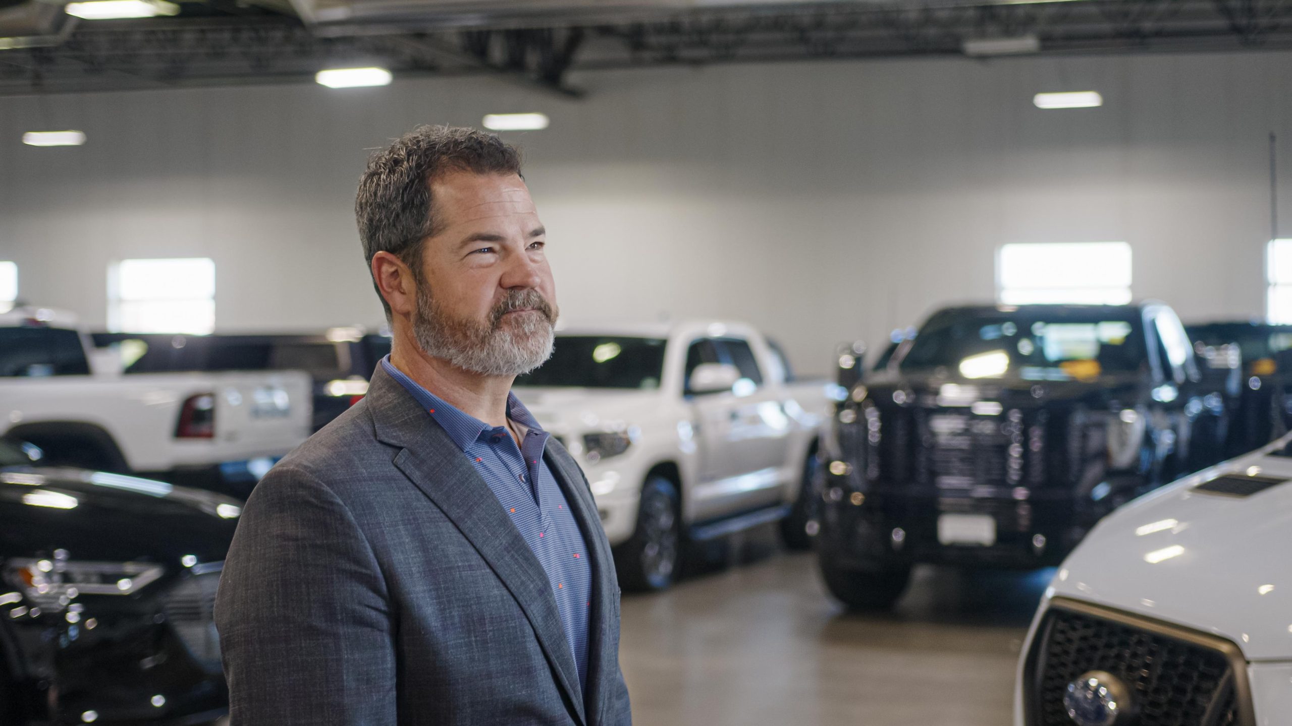 smiling man standing in front of used trucks for sale