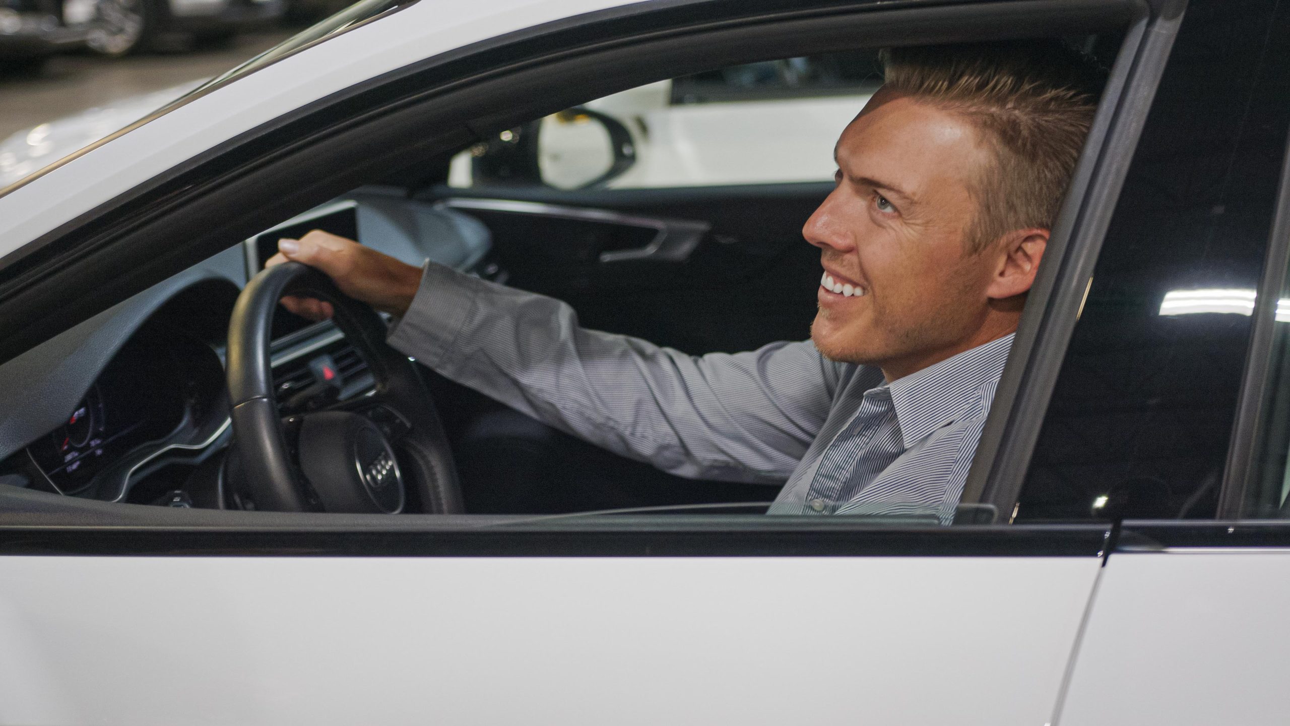 smiling man sitting in driver's seat of used car