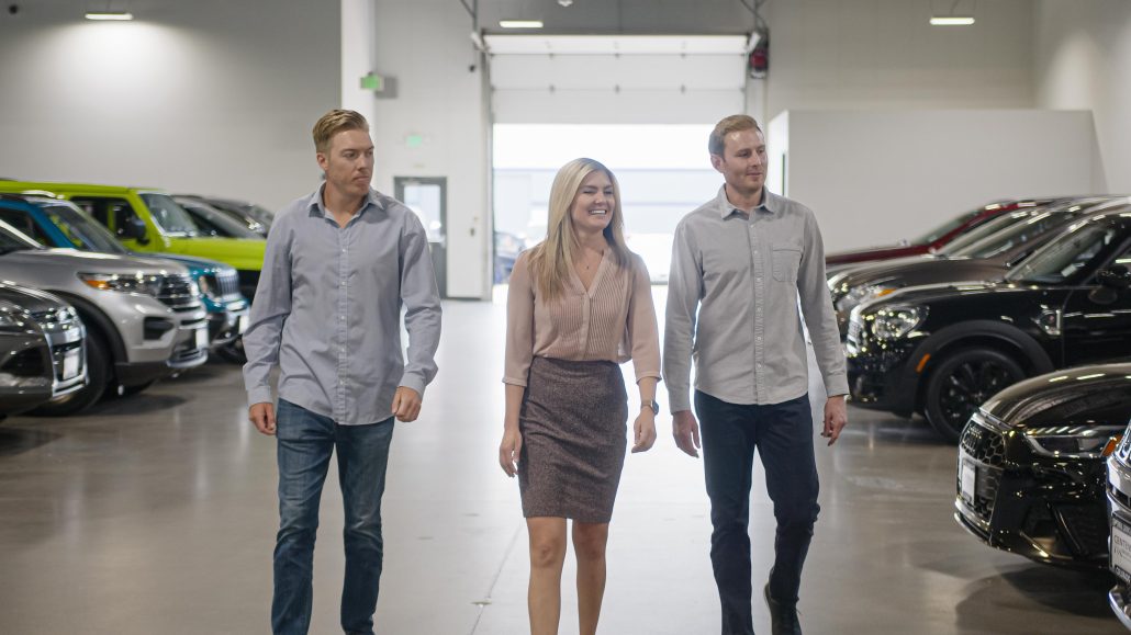 Three people walking through top-rated car dealership.